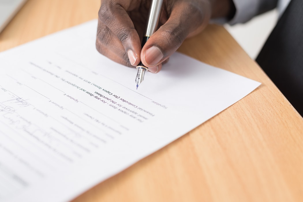 A close-up of a man signing a power of attorney agreement after receiving advice from Funeralocity in New Orleans, LA