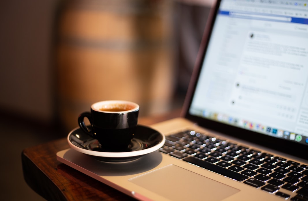 A small cup of coffee sitting on the edge of laptop