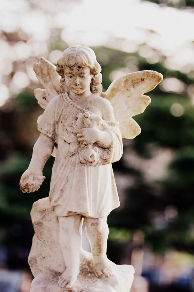An angel carved out of stone on a grave, symbolizing the cremation services offered by funeral homes on Funeralocity, a comparison website